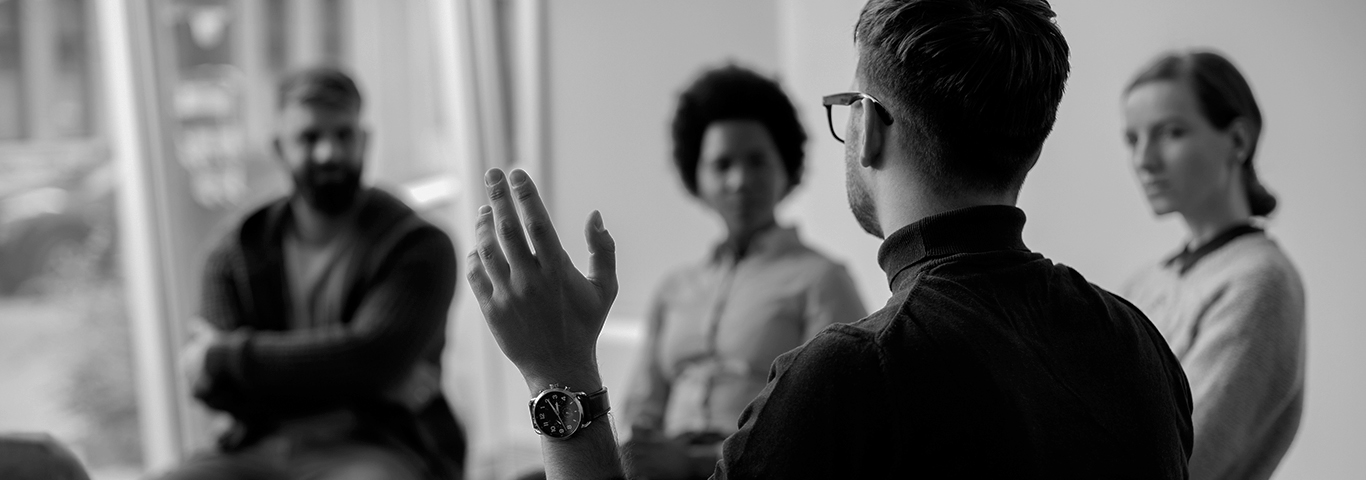 A group therapy session with everyone actively listening to a peer.